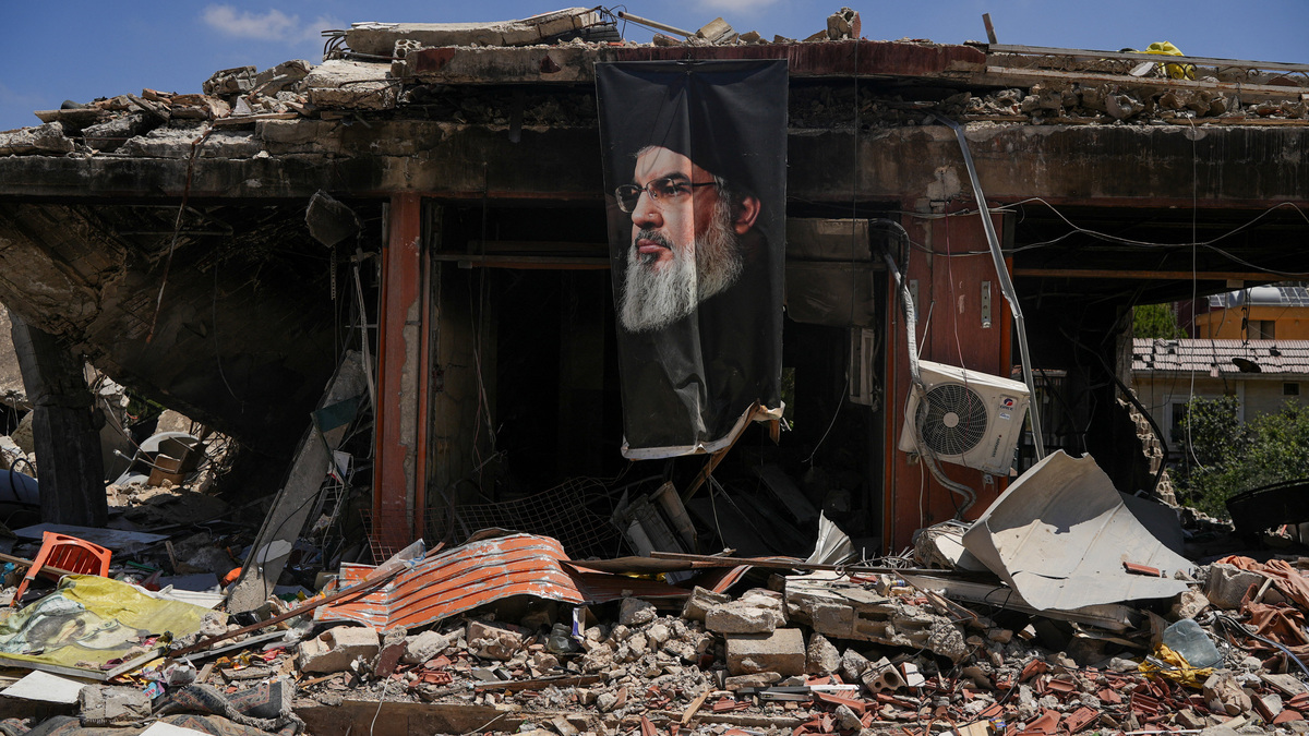 A banner with an image of late Hezbollah leader Hassan Nasrallah hangs from a destroyed building in Jibchit, Nabatieh district, Lebanon, June 16, 2026, following a deal between the United States and Iran. REUTERS/Stringer