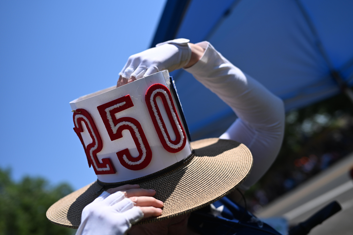 Laureen Gilroy adjusts her handmade 250 hat during the Greeley Stampede's Independence Day parade in Greeley, Colo., July 4, 2026. Though it was muggy and miserably hot in many parts of the country, the day was marked with the usual American exuberance, with fighter jets, tall ships, parachutists and flag-festooned pick-up trucks. (Mark Makela/The New York Times)