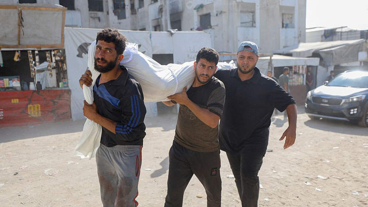 Palestinians carry the body of a victim killed in an Israeli strike behind Yemen Al-Saeed Hospital in Jabalia, northern Gaza Strip, on Sunday. Israeli strikes and gunfire killed at least six Palestinians in the Gaza Strip on Sunday, health officials said.