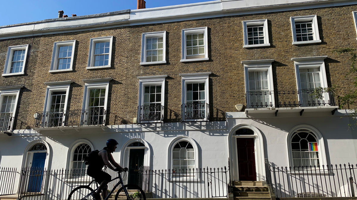 A person on a bicycle rides past houses on a street early in the morning in Islington, London, Britain, June 22, 2020.   REUTERS/Simon Newman