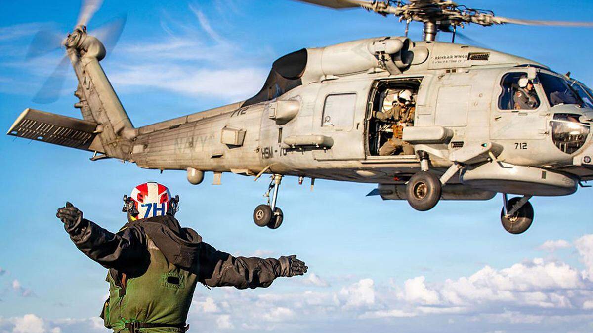 In this U.S. Navy released handout, a sailor signals the launch of an MH-60R Sea Hawk helicopter on the flight deck of the USS Gerald R. Ford at sea on Saturday.