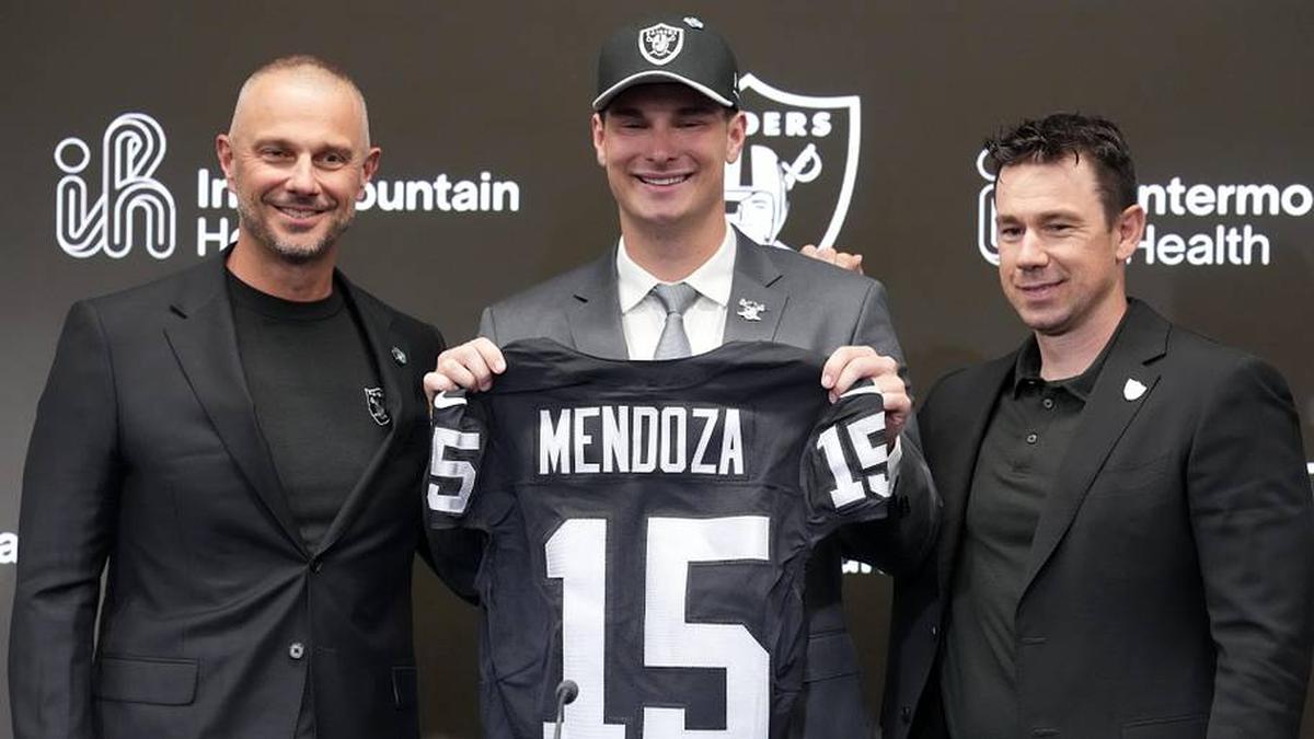  Apr 24, 2026; Henderson, NV, USA; Las Vegas Raiders quarterback Fernando Mendoza (center) poses with jersey at introductory press conference at Intermountain Health Performance Center flanked by general manager John Spytek (left) and head coach Klint Kubiak after being selected as the No. 1 pick in the 2026 NFL Draft. Mandatory Credit: Kirby Lee-Imagn Images | Kirby Lee-Imagn Images 