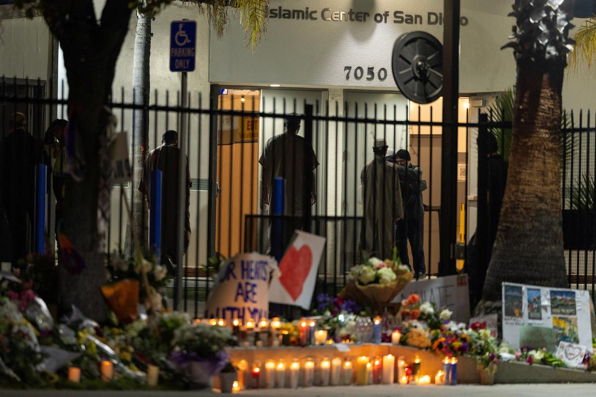 A security guard is hugged as people arrive for early morning call to prayer as the Islamic Center of San Diego opens for the first time following a shooting in San Diego, California, U.S., May 20, 2026. REUTERS/Mike Blake