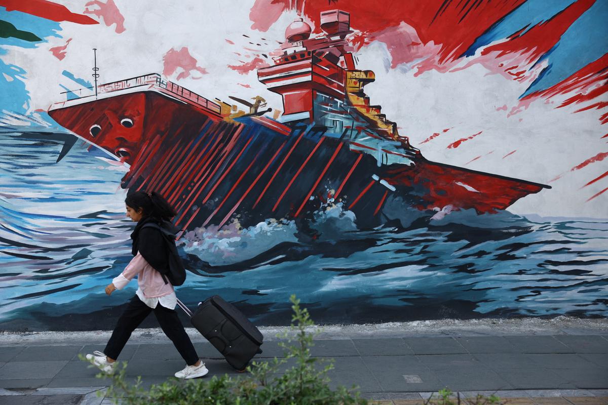 An Iranian woman walks next to a mural on a street in Tehran, Iran, May 11, 2026. Majid Asgaripour/WANA (West Asia News Agency) via REUTERS