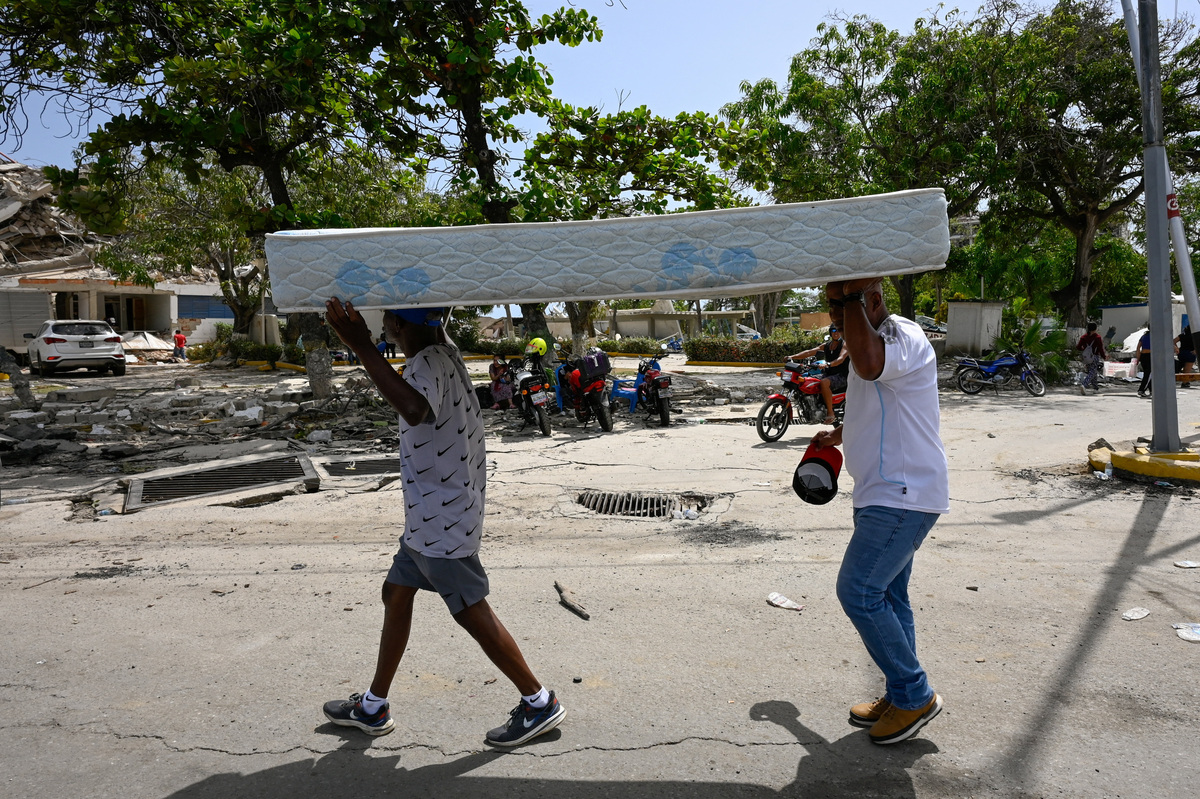 People carry a mattress along a street after earthquakes hit the country, in La Guaira, Venezuela, June 26, 2026. REUTERS/Maxwell Briceno