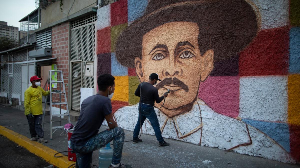El artista venezolano Miguel García da los últimos toques a su mural con la imagen del doctor José Gregorio Hernández, en Caracas, Venezuela, el 26 de abril de 2021. Conocido como el “médico de los pobres”, Hernández será beatificado el 30 de abril por la Iglesia católica, un paso hacia su santidad. (AP Foto/Ariana Cubillos)