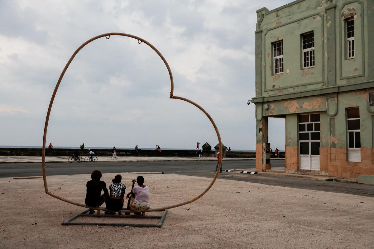 People sit in a heart-shaped public art installation at the seafront Malecon as Cuba's state-run economy has descended into a full-blown crisis after the administration of U.S. President Donald Trump hardened sanctions and cut off the Caribbean nation's oil supply, in Havana, Cuba, May 6, 2026. REUTERS/Norlys Perez