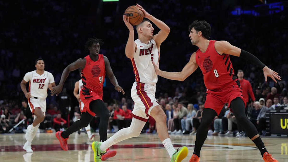 El jugador del Heat Nikola Jovic (centro) entra al aro ante la marca de Deni Avdija (8), de los Trail Blazers de Portland, celebrado el 8 de noviembre de 2025 en el Kaseya Center en Miami. 