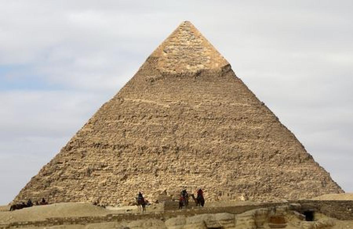 FILE PHOTO: Camel guides wait for customers in front of the Pyramid of Khufu, the largest of the Great Pyramids of Giza, on the outskirts of Cairo, Egypt January 18, 2020. REUTERS/Marius Bosch/File Photo