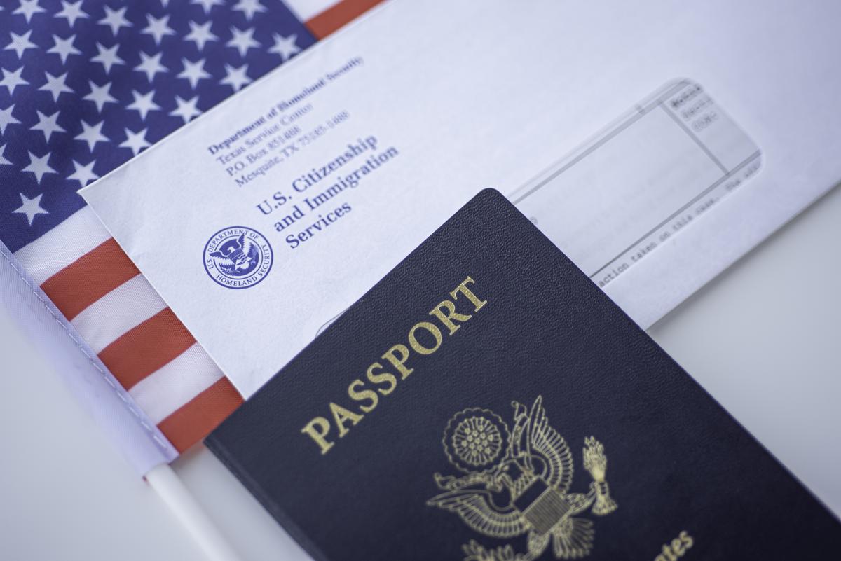  Passport of USA next to the Blurred Letter from USCIS and American flag. Close up view. (Getty Images) 
