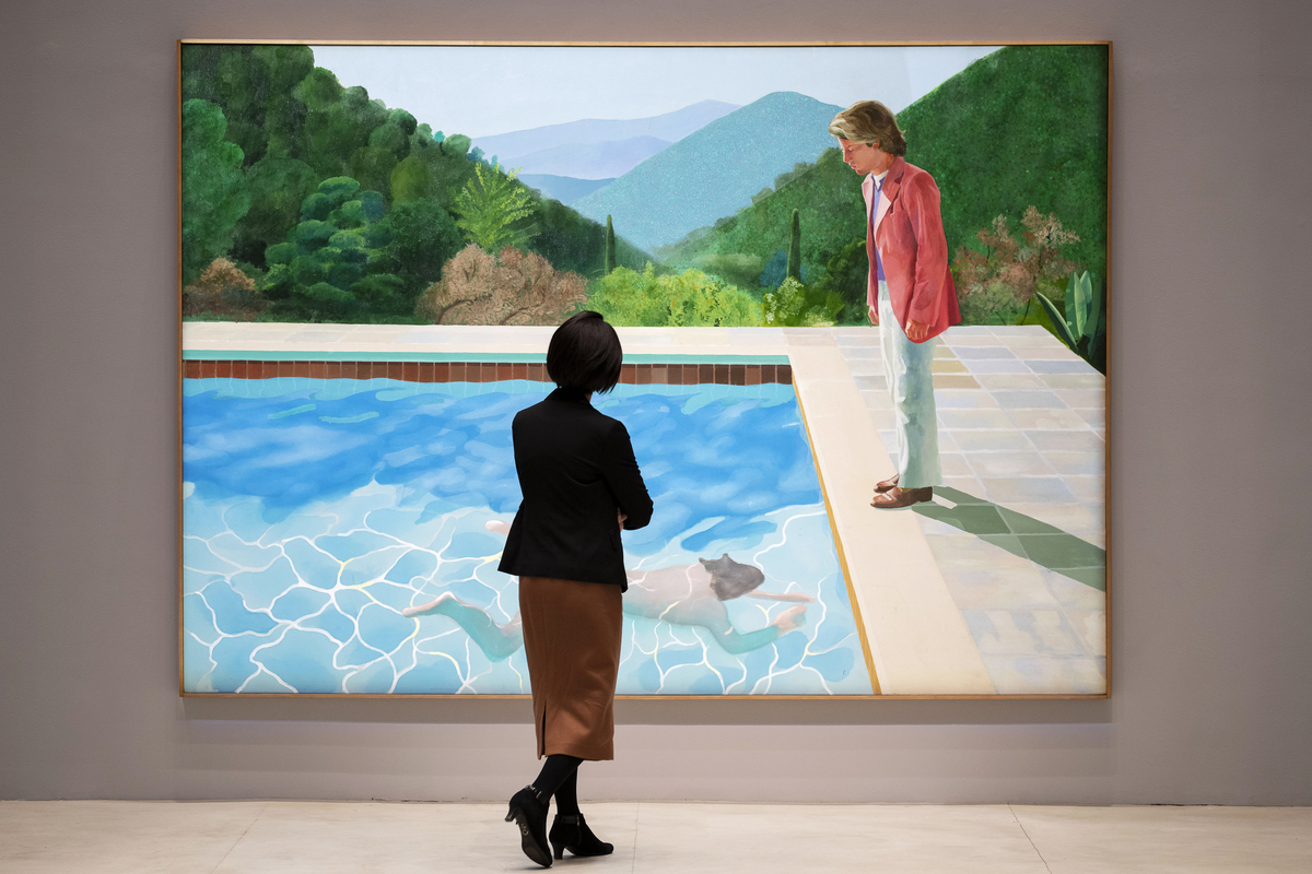 FILE -- A woman views David Hockney's "Portrait of an Artist (Pool with Two Figures)", the day before it was auctioned for $90 million, at Christie's in New York, Nov. 14, 2018. Hockney, whose colorful figurative paintings were both conservative and iconoclastic, defying the dominant abstract schools of the mid-20th century, died at home in London on June 11, 2026. He was 88. (Karsten Moran/The New York Times)