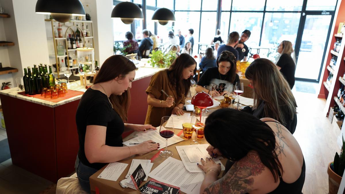 Melissa Clark, left, and fellow wine enthusiasts write postcards to members of Congress during a postcard-writing campaign to protest current presidential policies and executive orders, at Deep Red Wine Merchant, 2901 N. Milwaukee Ave., Chicago, on May 12, 2026. (John J. Kim/Chicago Tribune/TNS)