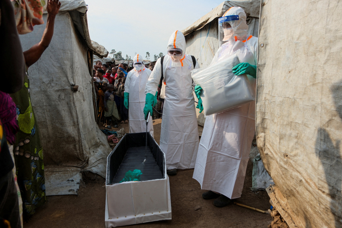 Health workers in full personal protective equipment (PPE) disinfect a coffin while preparing for the burial of suspected Ebola victims at the Kigonze displaced persons camp in Bunia, eastern Democratic Republic of Congo, on June 18, 2026, one month after the outbreak was declared. REUTERS/Gradel Muyisa Mumbere