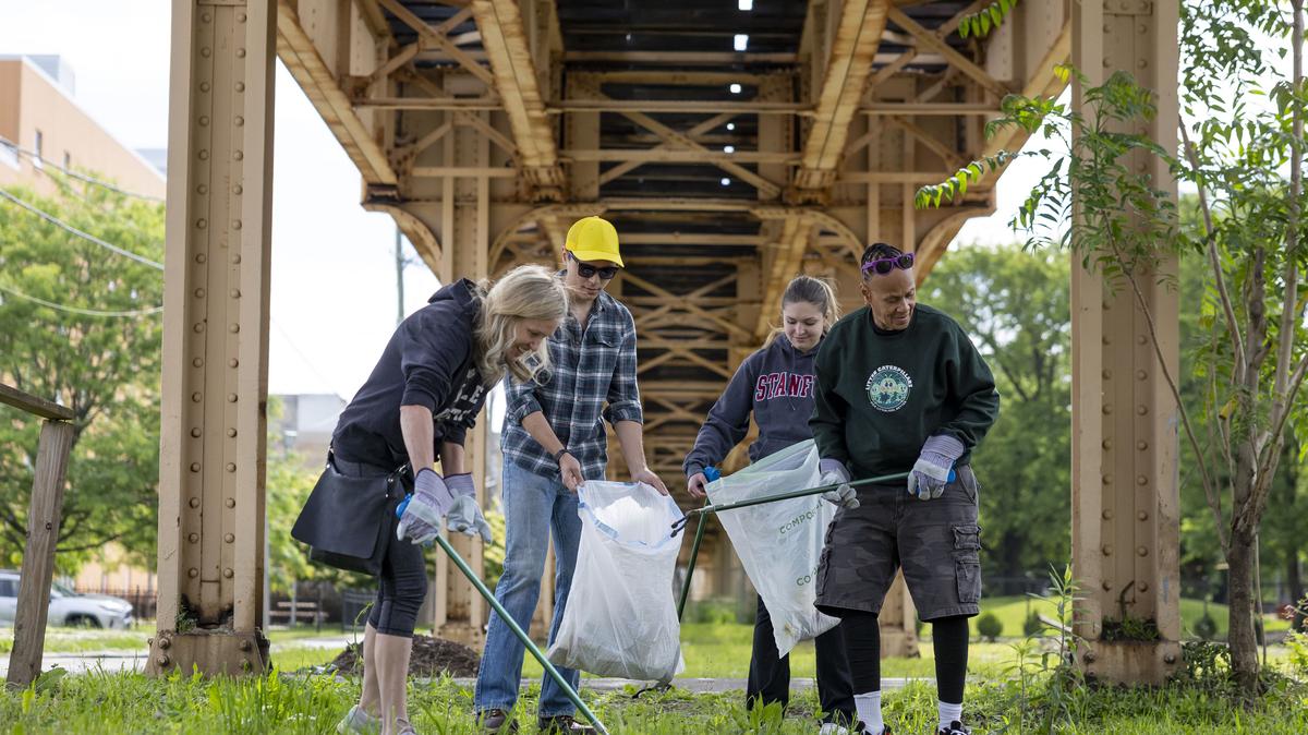 Volunteers Kara Blain, from left, David Bippes, Kaeden Beaty and Cora Rambert pick up trash on May 31, 2026, with the Litter Caterpillars group under the CTA “L” tracks next to their vacant lot park in Chicago’s Englewood neighborhood. (Brian Cassella/Chicago Tribune/TNS)