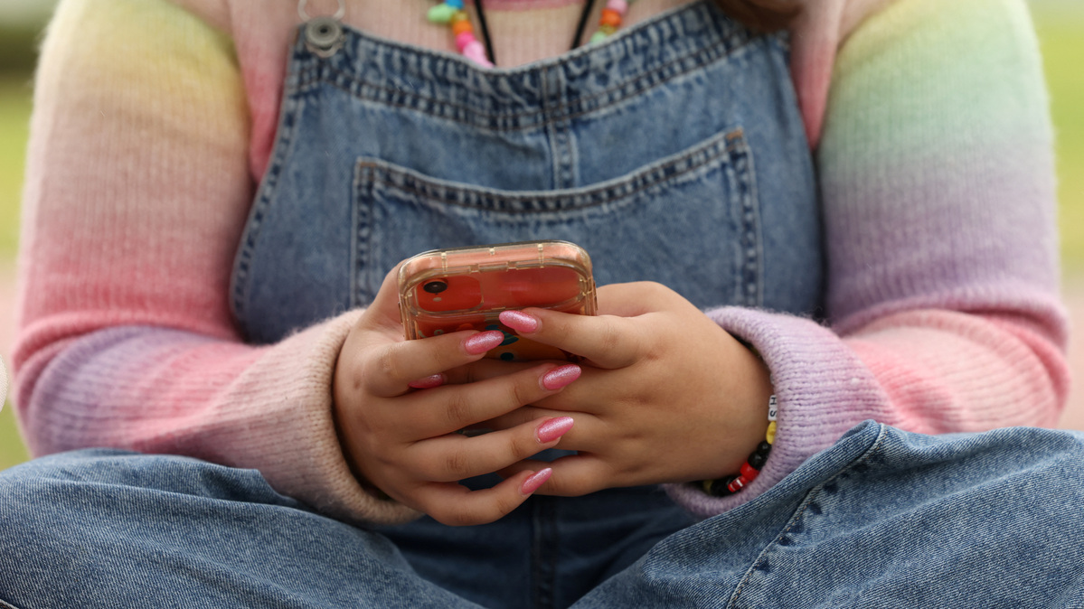A girl uses her mobile phone in Sydney, Australia, November 22, 2025. REUTERS/Hollie Adams