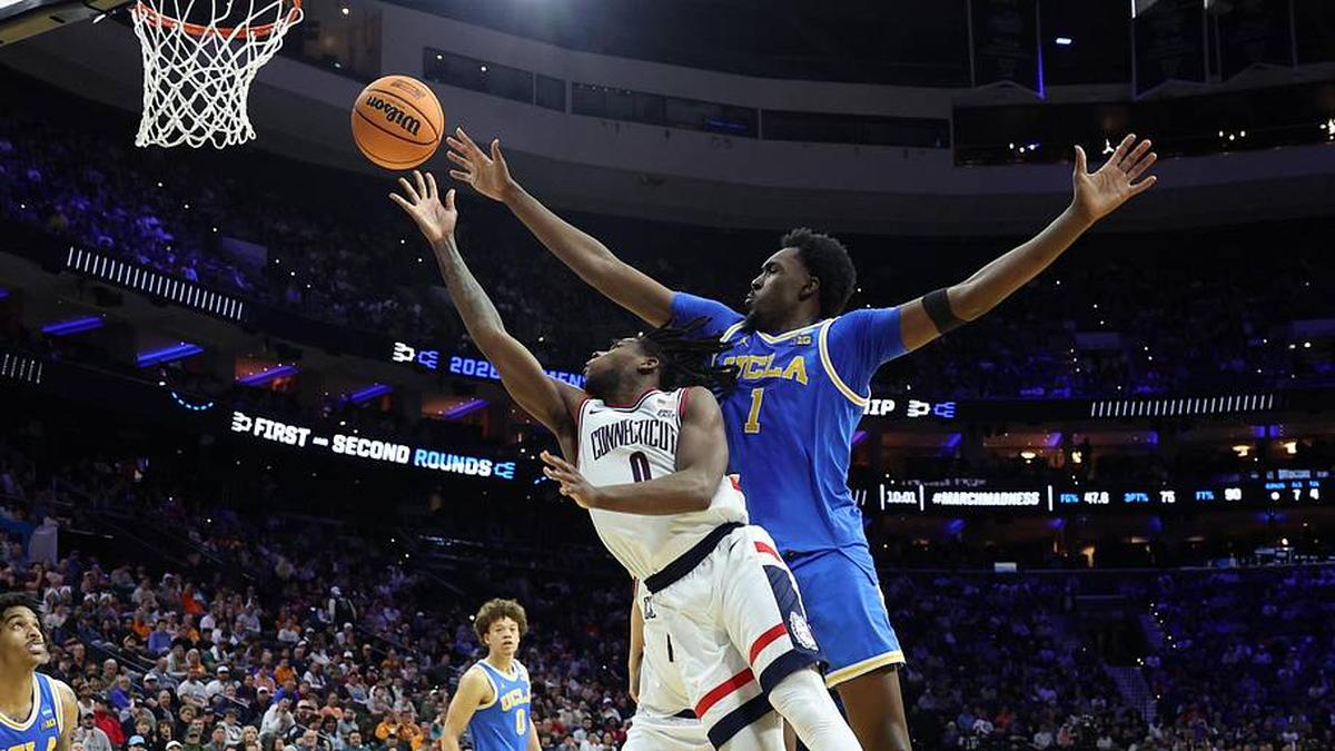 Mar 22, 2026; Philadelphia, PA, USA; UConn Huskies guard Malachi Smith (0) reaches for a rebound against UCLA Bruins center Xavier Booker (1) in the first half during a second round game of the men's 2026 NCAA Tournament at Xfinity Mobile Arena. Mandatory Credit: Bill Streicher-Imagn Images | Bill Streicher-Imagn Images 