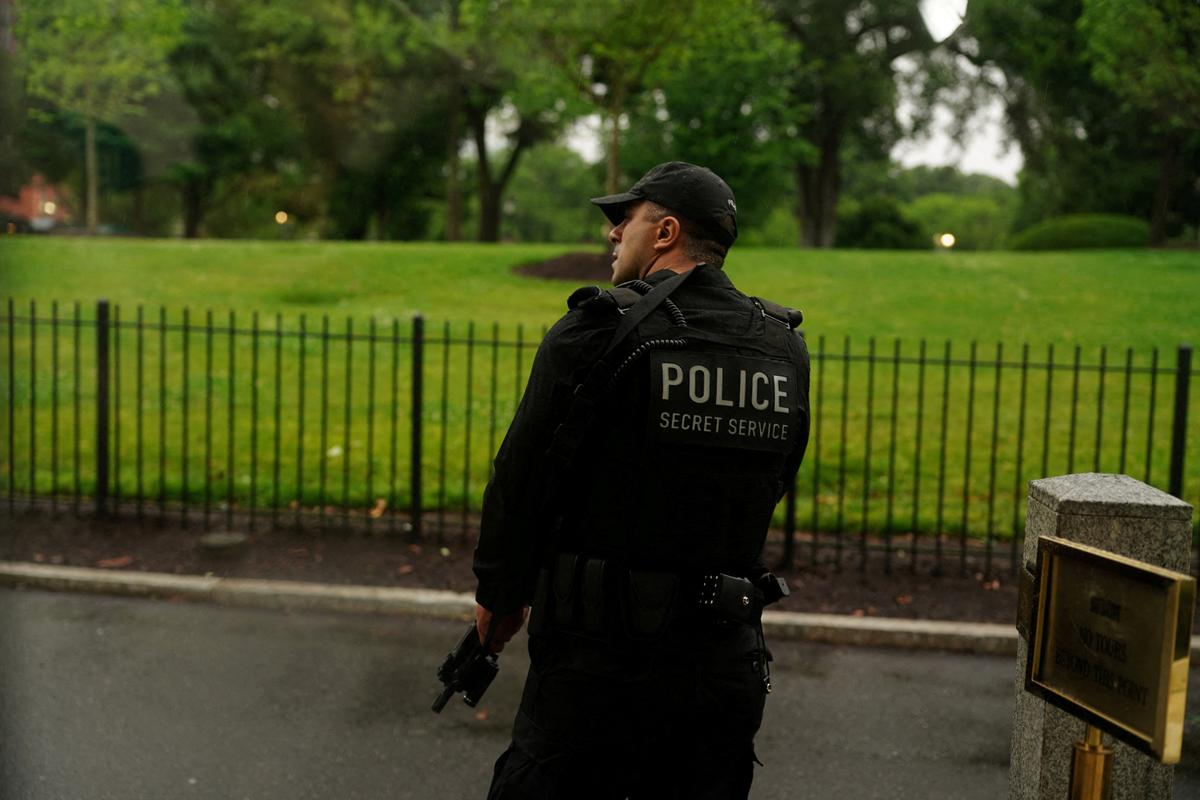 A member of the U.S. Secret Service watches holding his weapon after alleged gunfire was heard nearby, at the White House in Washington, D.C., U.S., May 23, 2026. REUTERS/Nathan Howard