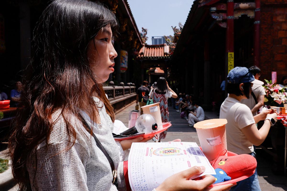 A BTS fan holds snacks, group merchandise, concert seat maps and a wish list as she prays to Yue Lao, the god of love in Chinese mythology who oversees relationships and marriage, at Taipei’s Bangka Lungshan Temple, in hopes of securing a concert ticket, in Taipei, Taiwan, May 30, 2026. REUTERS/Ann Wang