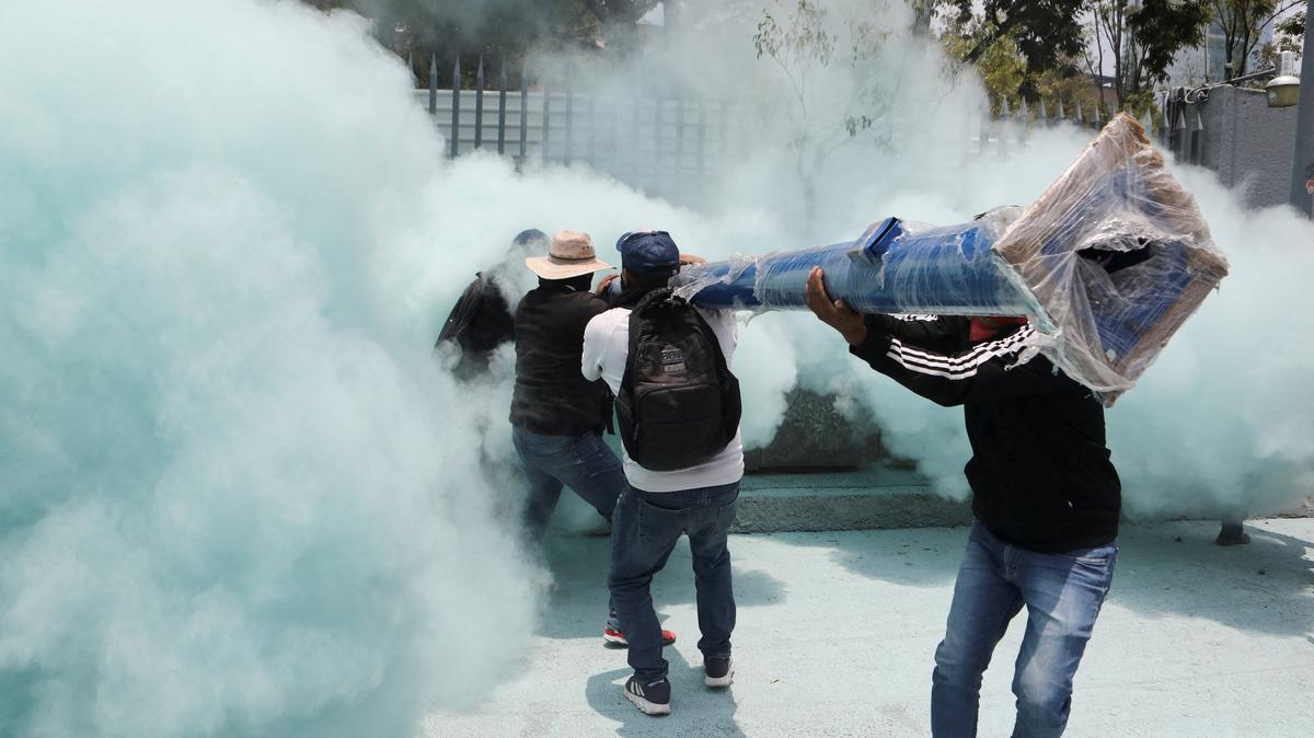 Dissident teachers from Mexico's National Coordination of Education Workers (CNTE) carry a light post as police use fire extinguisher smoke to disperse demonstrators outside the Secretariat of Public Education (SEP) during a protest to demand better wages and pensions, under the slogan "If there's no solution, the ball won't roll," ahead of the 2026 FIFA World Cup, in Mexico City, Mexico, June 3, 2026. REUTERS/Paola Garcia