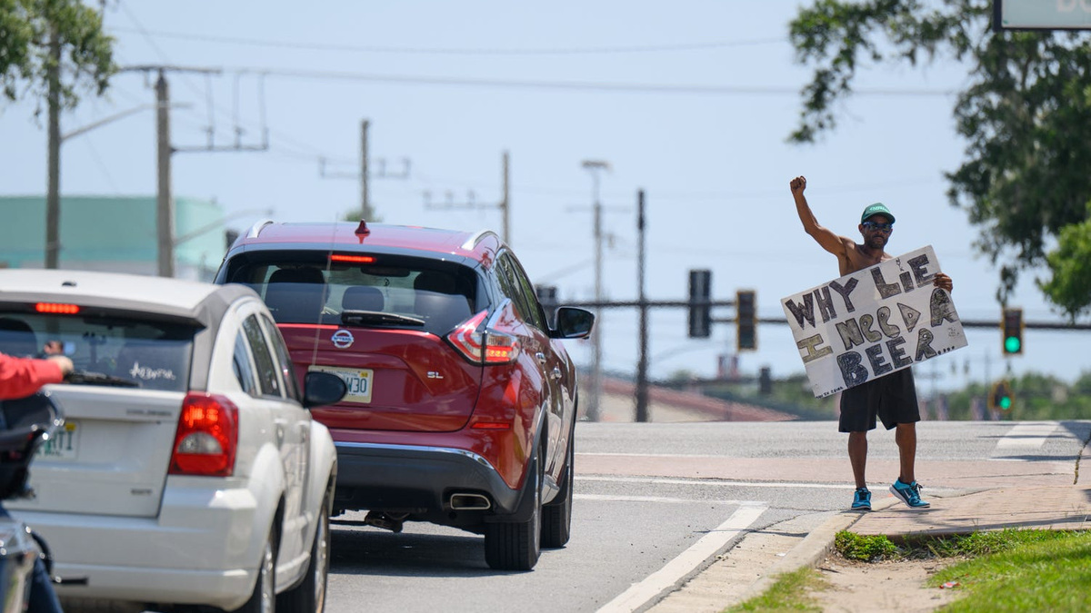 Steven Morehouse brandishes a sign asking for money to buy beer at the corner of International Speedway Boulevard and Ridgewood Avenue in Daytona Beach on June 29. The U.S. Court of Appeals for the 11th Circuit on June 25 agreed with a lower court that some parts of the Daytona Beach panhandling laws violate the First Amendment.