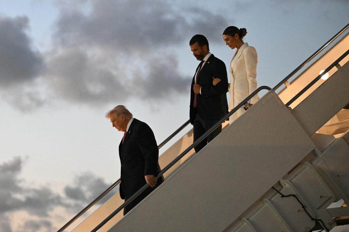 President Donald Trump, followed by Donald Trump Jr. and Bettina Anderson step off Air Force One.