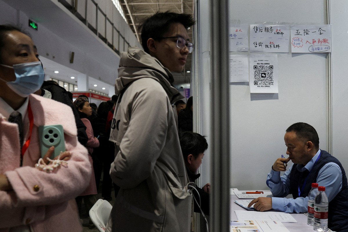 FILE PHOTO: A recruiter attends to an applicant at a job fair in Beijing, China March 14, 2026. REUTERS/Florence Lo/File Photo