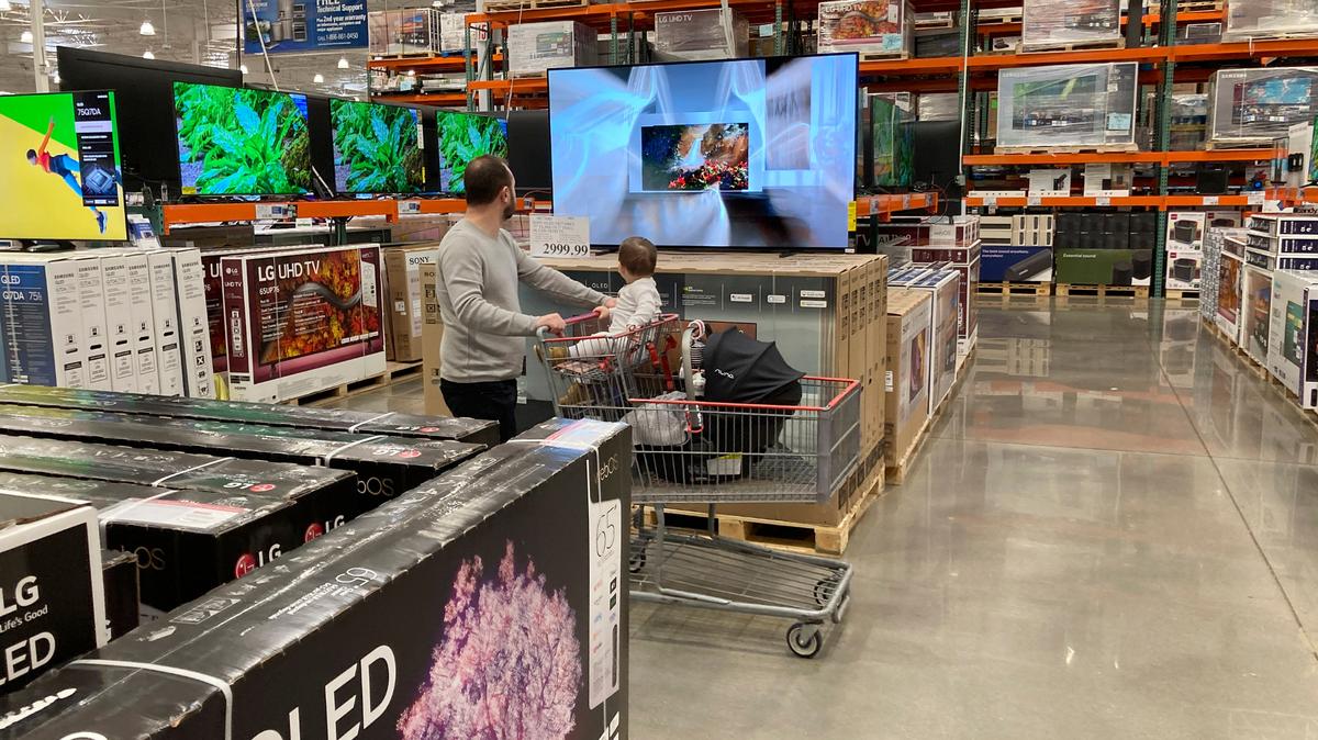 Un comprador empuja a un niño en un carrito mientras mira televisores de pantalla grande en exhibición en la sección de productos electrónicos de un almacén de Costco, el martes 29 de marzo de 2022, en Lone Tree, Colorado. Hasta ahora, los consumidores estadounidenses han desafiado los precios más altos de la gasolina, los alimentos , y alquiler y han estado gastando más en 2022, brindando un apoyo crucial a la economía. El tiempo que pueda continuar será uno de los factores clave que afectarán la economía y la inflación este año. (Foto AP/David Zalubowski)