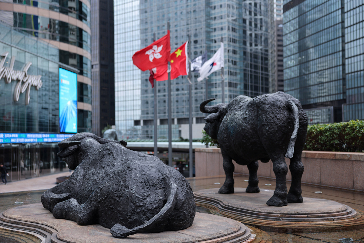 Bull statues near screens showing the Hang Seng stock index and stock prices outside Exchange Square, in Hong Kong, China, February 3, 2026. REUTERS/Tyrone Siu