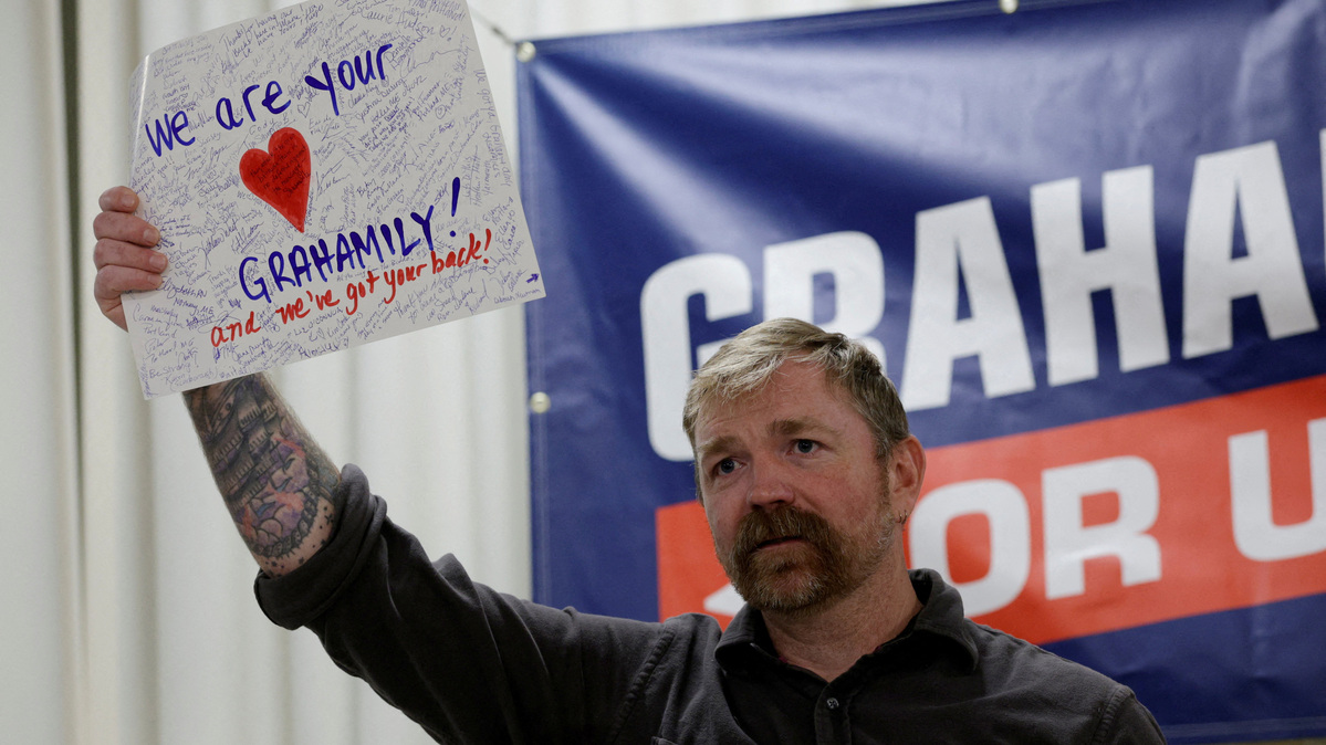 FILE PHOTO: Democratic candidate for U.S. Senate Graham Platner holds up a handmade card given to him by an audience member reading ?We Are your Grahamily And We?ve Got Your Back? during a campaign town hall meeting in Portland, Maine, U.S., June 7, 2026. REUTERS/Brian Snyder/File Photo