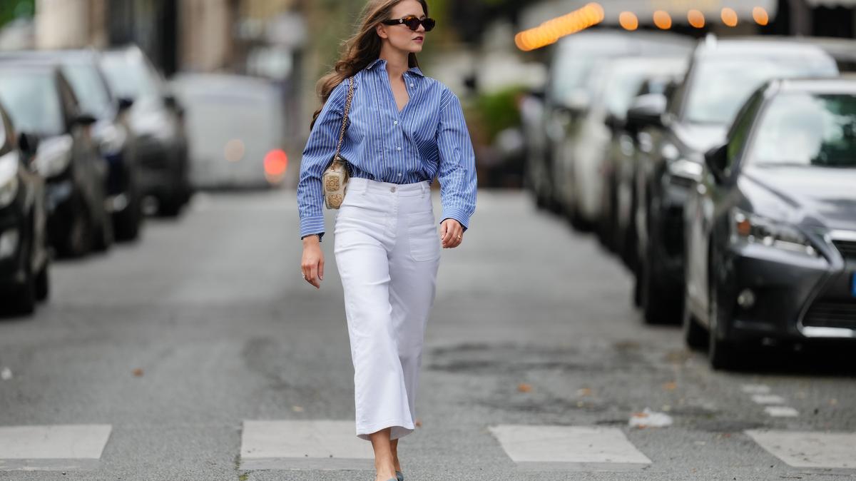 PARIS, FRANCE - MAY 20: Segolene Hyppolite wears sunglasses, a blue and white oversized shirt from Tommy Hilfiger, a raffia beige bag from Vanessa Bruno, high waist white denim pants from Vanessa Bruno, Chanel slingback shoes in blue denim with black tips, during a street style fashion photo session, on May 20, 2024 in Paris, France. (Photo by Edward Berthelot/Getty Images)