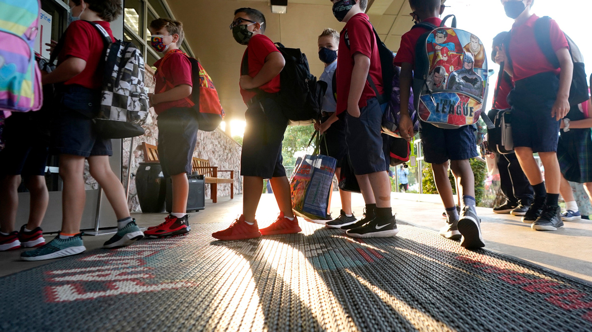 Wearing masks to prevent the spread of COVID-19, elementary school students line up to enter school for the first day of classes in Richardson, Texas, Tuesday, Aug. 17, 2021. Despite Texas Gov. Greg Abbott’s executive order banning mask mandates by local officials, the Richardson Independent School District and many others across the state are requiring masks for students. (AP Photo/LM Otero)