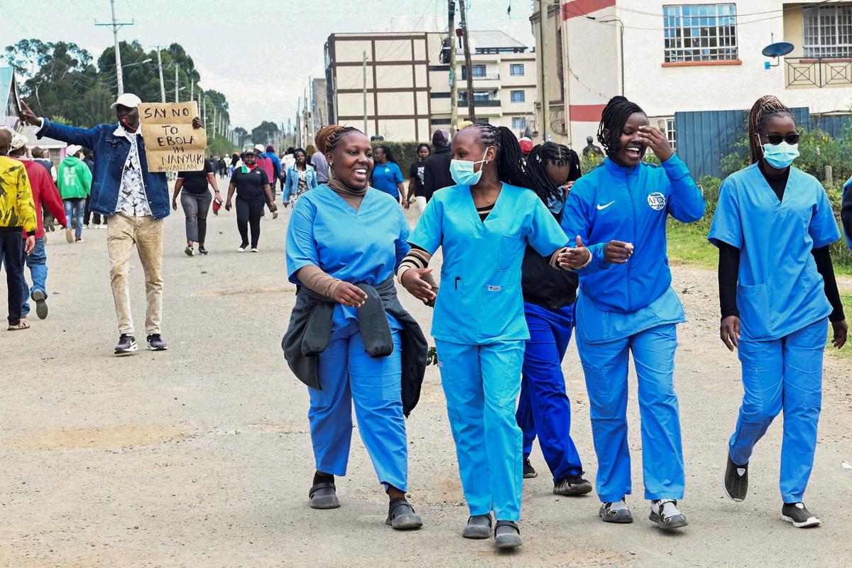 FILE PHOTO: Women dressed in scrubs walk along the street as demonstrators participate during a protest against a U.S.-backed Ebola quarantine plan on the establishment of a 50-bed facility at a Kenyan air force base that was intended to host Americans exposed to Ebola, in Nanyuki town, in Laikipia County, Kenya June 1, 2026. REUTERS/John Muchucha/File Photo