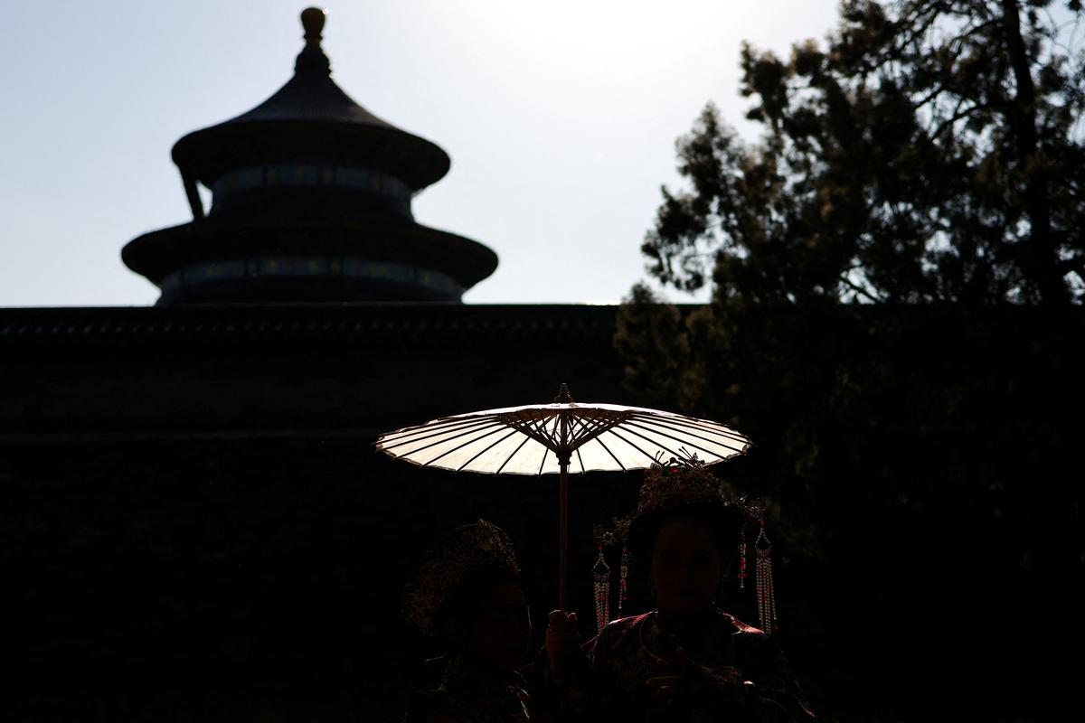 Women dressed in traditional dress pose for pictures next to the Hall of Prayer for Good Harvests at the Temple of Heaven, or Tiantan Park, ahead of this week’s U.S. President Donald Trump's visit to China, in Beijing, China, May 11, 2026. REUTERS/Maxim Shemetov