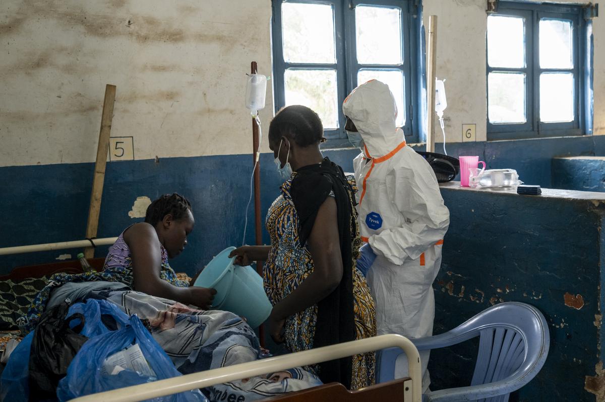 A relative and a medical worker care for Christiane Bahati shortly before she fell into a coma and died, at a hospital's Ebola ward in the mining town of Mongbwalu, Democratic Republic of Congo, May 26, 2026. In a remote gold mining town at the epicenter of the Ebola outbreak, medical workers struggle to beat back a surge of deaths and infections. (Arlette Bashizi/The New York Times)