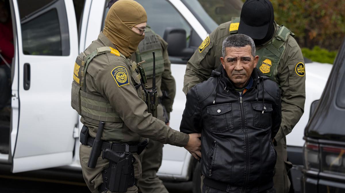 U.S. Border Patrol agents transfer a man they took from an H-Mart parking lot into a van in a Niles, Ill., on Oct. 31, 2025, during immigration enforcement operations. (Brian Cassella/Chicago Tribune/TNS)