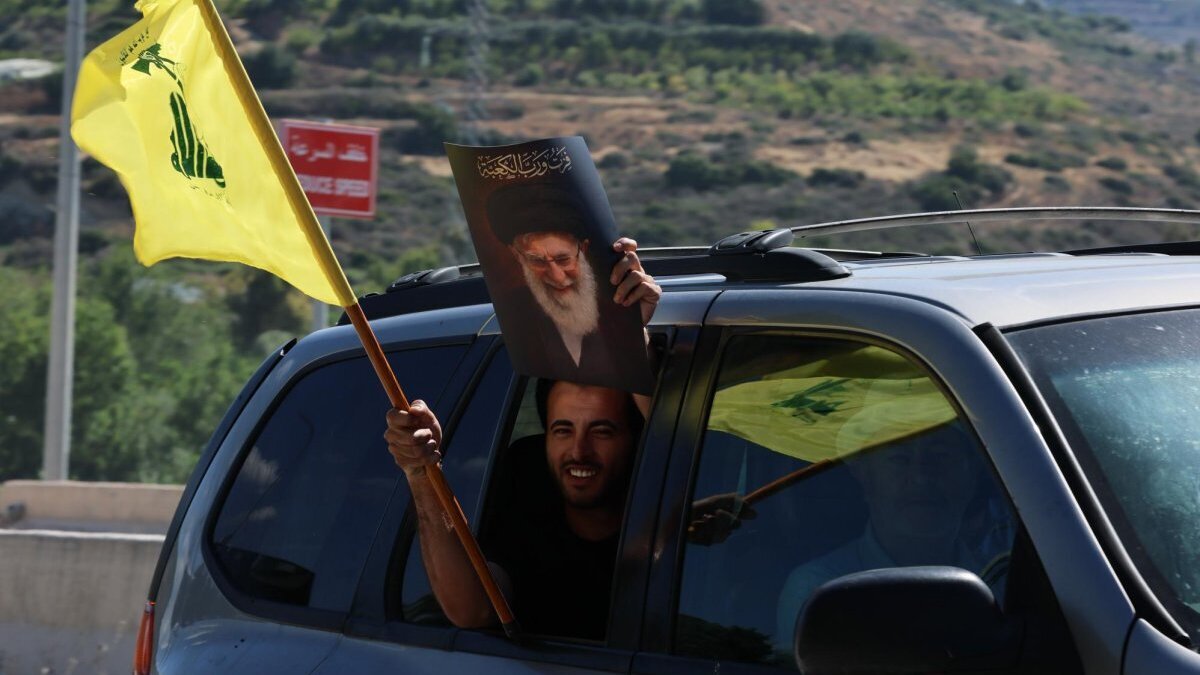 A Hezbollah supporter waves a Hezbollah flag and a poster of Iran’s founder Ayatollah Ruhollah Khomeini at Qasmiyeh Bridge, southern Lebanon, Friday. Fighting between Israel and Hezbollah continues, angering Iran. Photo by Wael Hamzeh/EPA