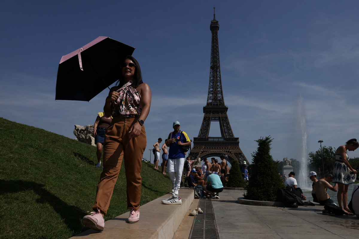 A person shelters under an umbrella by the Eiffel Tower during high temperatures amid a heatwave in Paris, France, June 27, 2026. REUTERS/Tom Nicholson