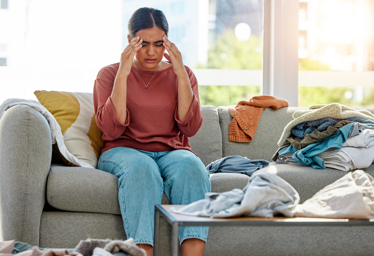  A stock image shows a woman sitting on a couch in a cluttered room. 