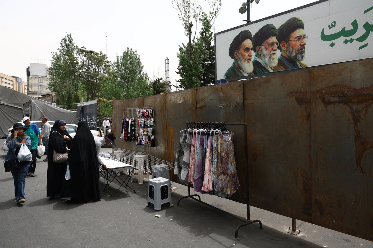 People walk past a banner depicting the late leader of the Islamic Revolution Ayatollah Ruhollah Khomeini, late Supreme Leader of Iran Ayatollah Ali Khamenei and Iran's new Supreme Leader Mojtaba Khamenei, in Tajrish Square in Tehran, Iran, May 4, 2026. Majid Asgaripour/WANA (West Asia News Agency) via REUTERS