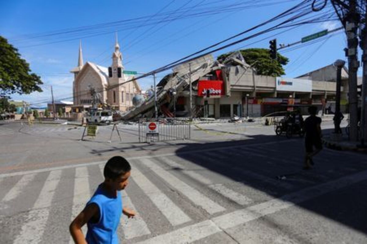 People walk near a collapsed building following the magnitude 7.8 quake in General Santos, southern Philippines, June 8, 2026. REUTERS/Manman Dejeto