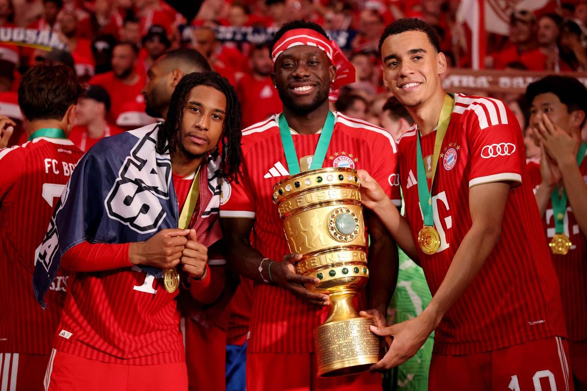  Michael Olise, Alphonso Davies and Jamal Musiala of FC Bayern Munich pose for a photo with the DFB Cup trophy following victory in the DFB Cup Final 2026 match between FC Bayern München and VfB Stuttgart at Olympiastadion on May 23, 2026 in Berlin, Germany. (Photo by Alex Grimm/Getty Images) Photo by Alex Grimm/Getty Images