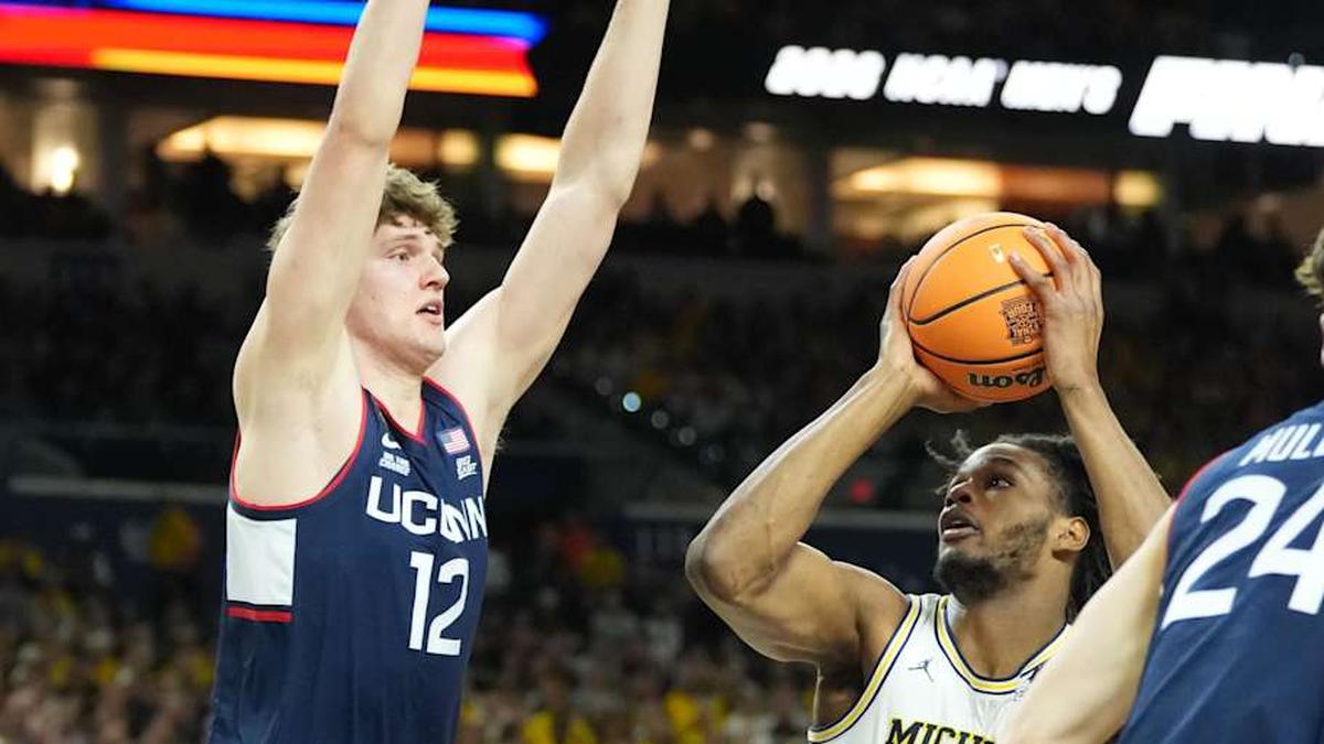  Apr 6, 2026; Indianapolis, IN, USA; Michigan Wolverines forward Morez Johnson Jr. (21) is defended by Connecticut Huskies center Eric Reibe (12) in the first half during the national championship of the Final Four of the men's 2026 NCAA Tournament at Lucas Oil Stadium. | Robert Deutsch-Imagn Images 