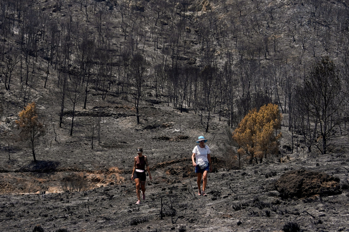 People walk around an area in the aftermath of deadly wildfires in Bedar, Almeria, Spain July 13, 2026. REUTERS/Ana Beltran