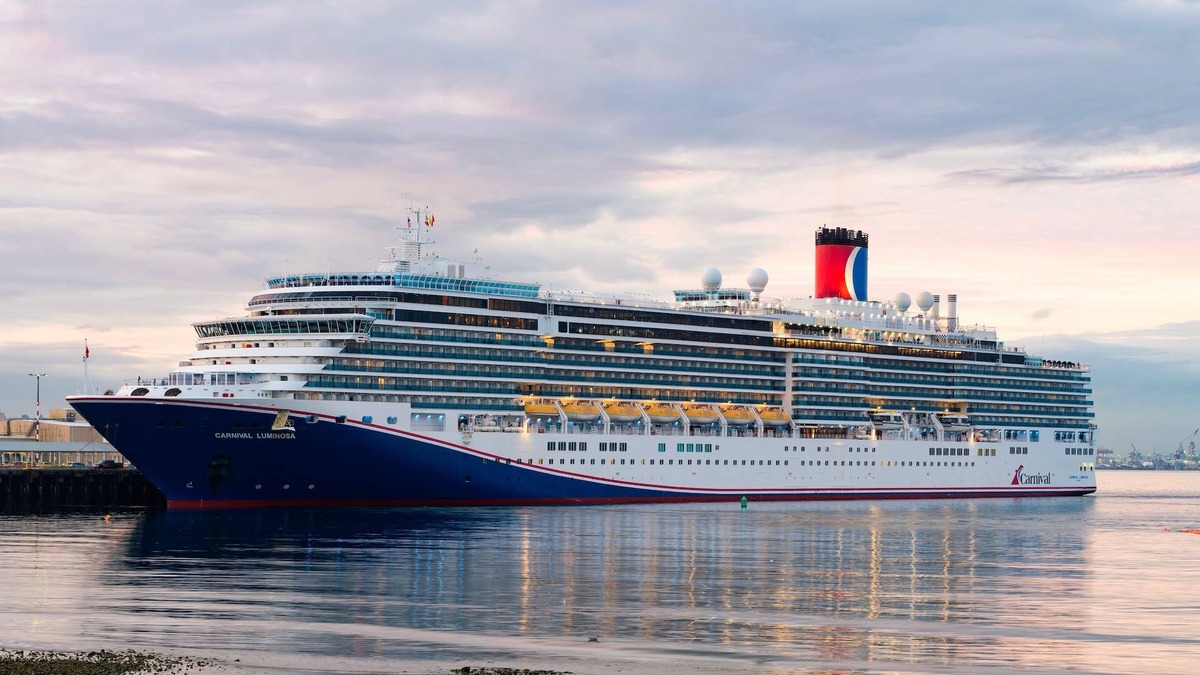 Carnival Luminosa docked at Pier 91 Seattle in dawn light with water reflection. 