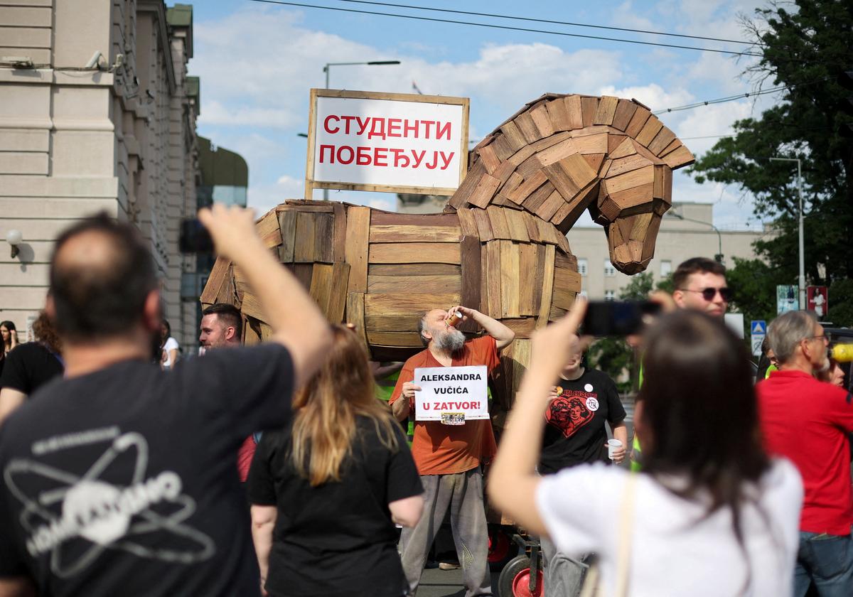 A man holds a sign reading "Aleksandar Vucic to prison", referring to the Serbian president, next to a mock Trojan horse with a sign that reads "The students are winning", on the day of a student-led protest demanding snap parliamentary elections, as Serbia's anti-corruption movement enters a new phase, following the Novi Sad railway station canopy collapse that killed 16 people in 2024, in Belgrade, Serbia, May 23, 2026. REUTERS/Djordje Kojadinovic