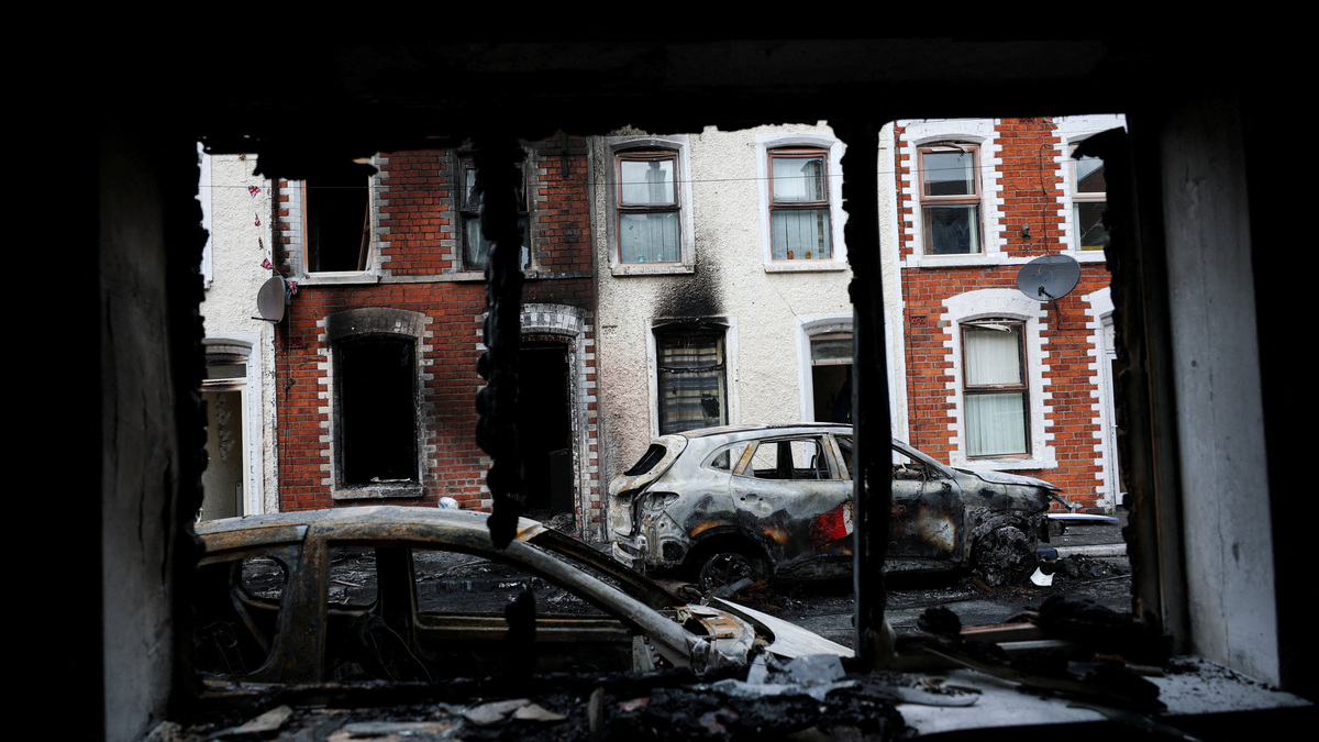 Damaged cars and a building are seen through a burnt window, in the aftermath of anti-immigrant protests following a knife attack on June 8, which left a man seriously injured and prompted police to declare a critical incident, at Lendrick Street, east Belfast, Northern Ireland, June 10, 2026. REUTERS/Isabel Infantes