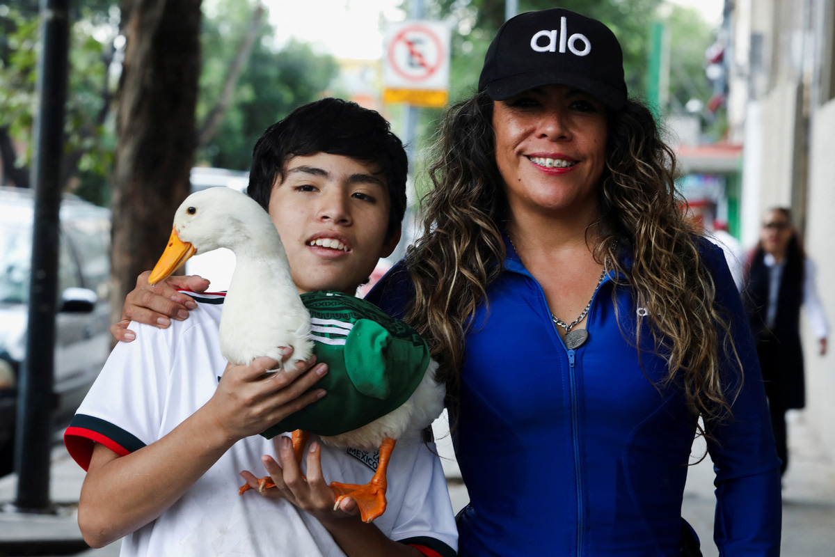 Karla Gomez and her son Christian pose with Merlin, a duck, wearing a Mexico national football team ('El Tri') jersey, that shot to fame after a chance encounter on Reforma Avenue went viral following the FIFA 2026 match between Mexico and South Africa, in Mexico City, Mexico, June 16, 2026. REUTERS/Paola Garcia