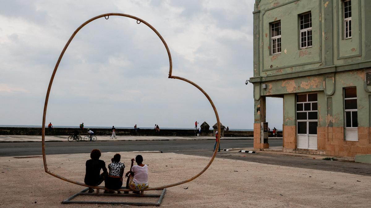 People sit in a heart-shaped public art installation at the seafront Malecon as Cuba's state-run economy has descended into a full-blown crisis after the administration of U.S. President Donald Trump hardened sanctions and cut off the Caribbean nation's oil supply, in Havana, Cuba, May 6, 2026. REUTERS/Norlys Perez