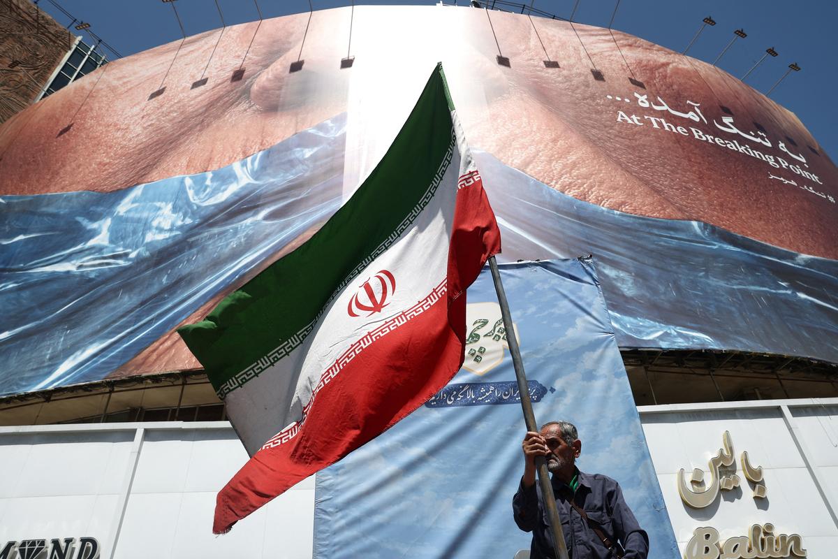 A man holds an Iranian flag near an anti-U.S. billboard depicting U.S. President Donald Trump and the Strait of Hormuz, in Tehran, Iran, May 30, 2026. Majid Asgaripour/WANA (West Asia News Agency) via REUTERS