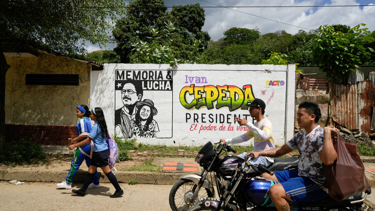 People walk past electoral advertisements ahead of the 21 June runoff between right-wing presidential candidate Abelardo De La Espriella and leftist candidate Ivan Cepeda, in Tubara, Colombia, June 10, 2026. REUTERS/Charlie Cordero